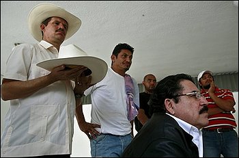 Honduras' ousted President Manuel Zelaya, right, watches a protest of his supporters on TV at the Brazilian embassy in Tegucigalpa, while one of his supporters holds his hat Thursday, Oct. 29, 2009. Honduras' opposing political factions resumed talks Thursday and expressed hope that a deal could be reached soon to end the power crisis that has paralyzed the country since a coup four months ago. (AP Photo/Esteban Felix)